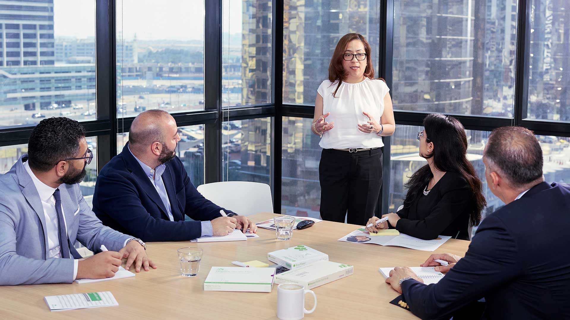 Flere ansatte lytter til en kvinnelig leder på et kontormøte